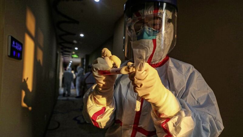 The stuff of science fiction? Unfortunately not. Here a medical worker writes on a tube after collecting a sample for testing from a suspected virus patient in Wuhan, China, earlier this week. Picture by Chinatopix/AP 