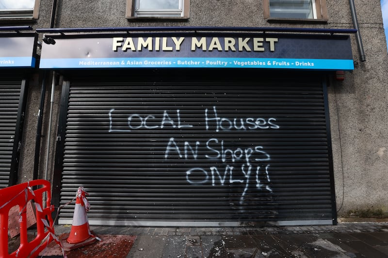 Racist graffiti outside a shop on the Donegall Road that was also targeted in an arson attack. Picture, PA/Liam McBurney