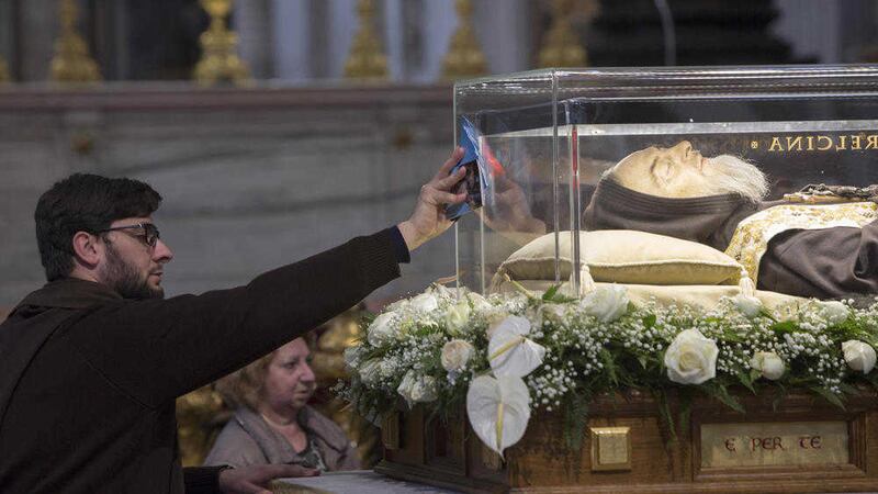 A friar touches the box containing the remains of St Pio in St Peter&#39;s Basilica. Picture by AP 
