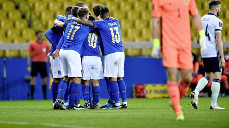 Italy players celebrate after Domenico Berardi scores their first goal as Northern Ireland goalkeeper Bailey Peacock-Farrell looks dejected. 