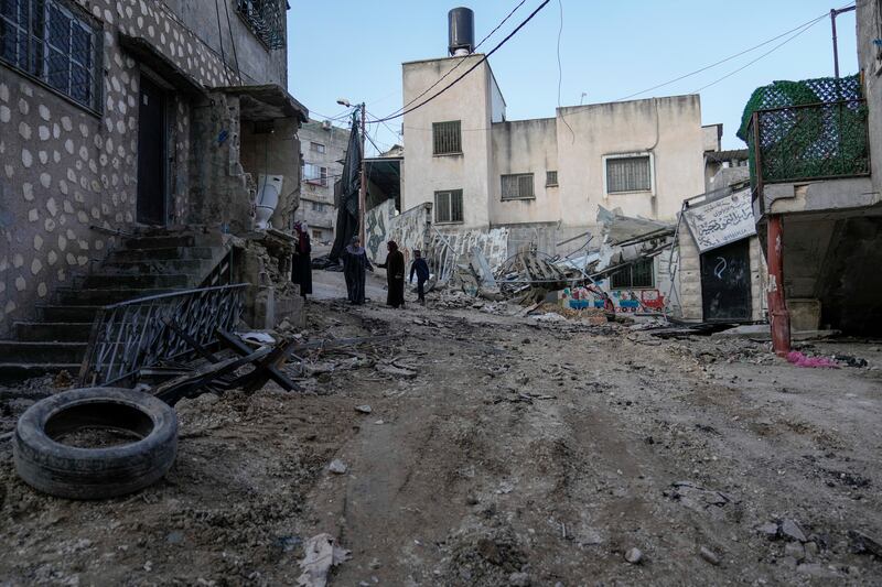 Palestinians walk through the aftermath of the Israeli military raid on Nur Shams refugee camp in the West Bank (Majdi Mohammed/AP)