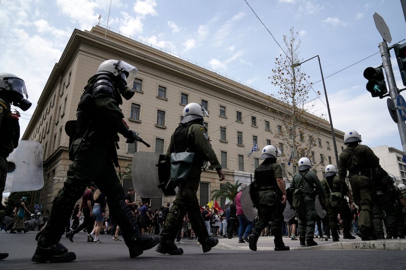 Riot police flank protesters during a rally in Athens (Thanassis Stavrakis/AP)