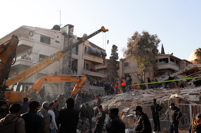 Emergency services work at a building hit by an air strike in Damascus (Omar Sanadiki/AP)