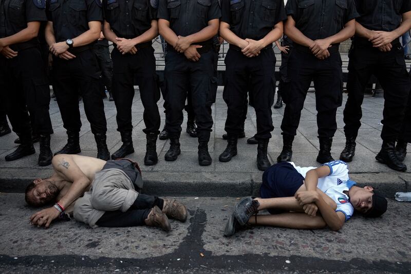 Police form a cordon on the perimeters of Congress as demonstrators lie at their feet (Rodrigo Abd/AP)