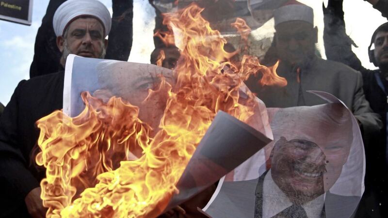 Palestinians burn posters of Israeli Prime Minister Benjamin Netanyahu and US President Donald Trump, during a protest against the US decision to recognize Jerusalem as Israel&#39;s capital, in Gaza City Thursday PICTURE: Khalil Hamra/AP 