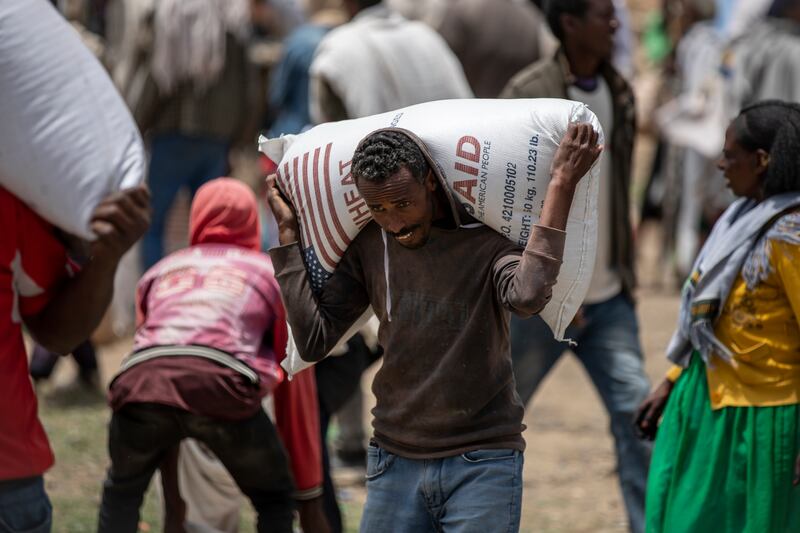 An Ethiopian man carries a sack of wheat on his shoulders to be distributed by the Relief Society of Tigray in the town of Agula (AP Photo/Ben Curtis, File)