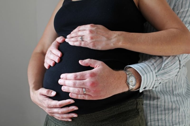Man and woman's hands on her pregnancy bump
