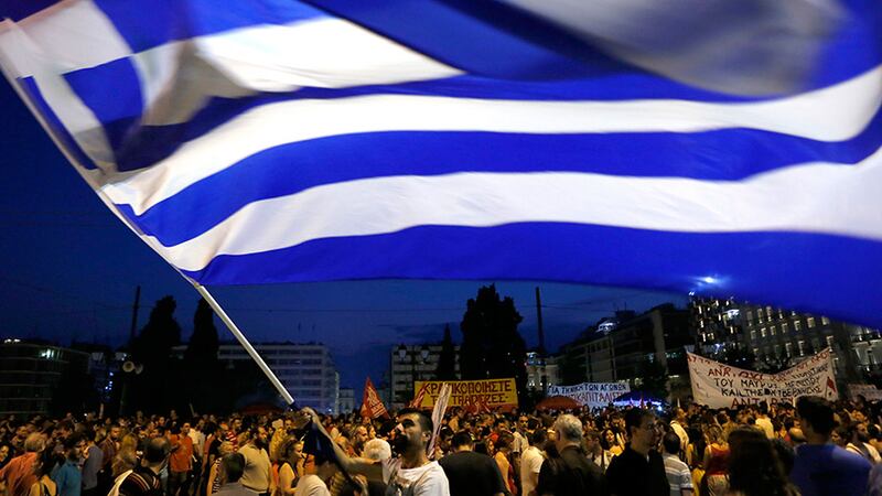 A demonstrator waves a Greek flag during an anti-austerity rally in central Athens. Eurozone leaders announced today that a bailout package for Greece has been agreed