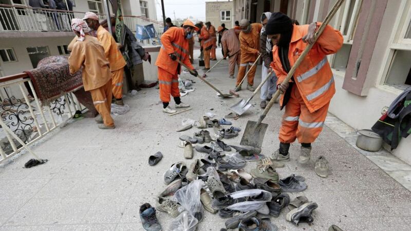 Afghan Municipality workers collect shoes of victims in front the Baqir-ul Ulom mosque after a suicide attack, in Kabul, Afghanistan. Picture by Rahmat Gul, Associated Press