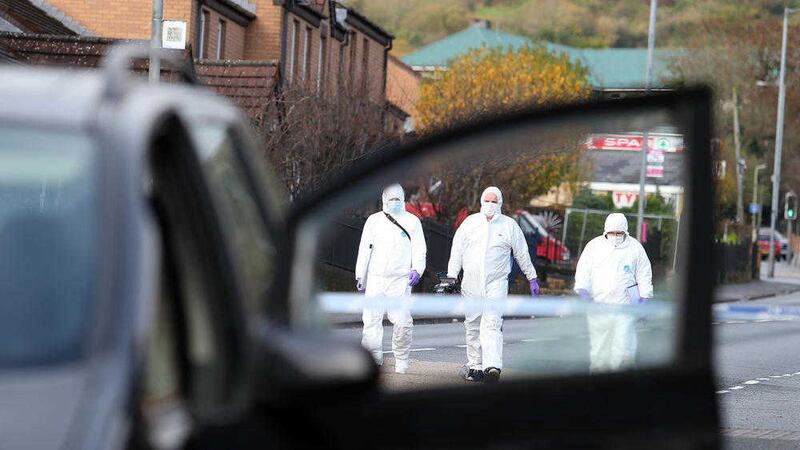 Forensics investigators examine a car on the Shaws Road in west Belfast where a man was shot in the head 