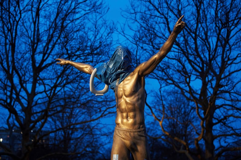 A blue plastic bag and a toilet seat hangs from the statue of Zlatan Ibrahimovic in Malmo