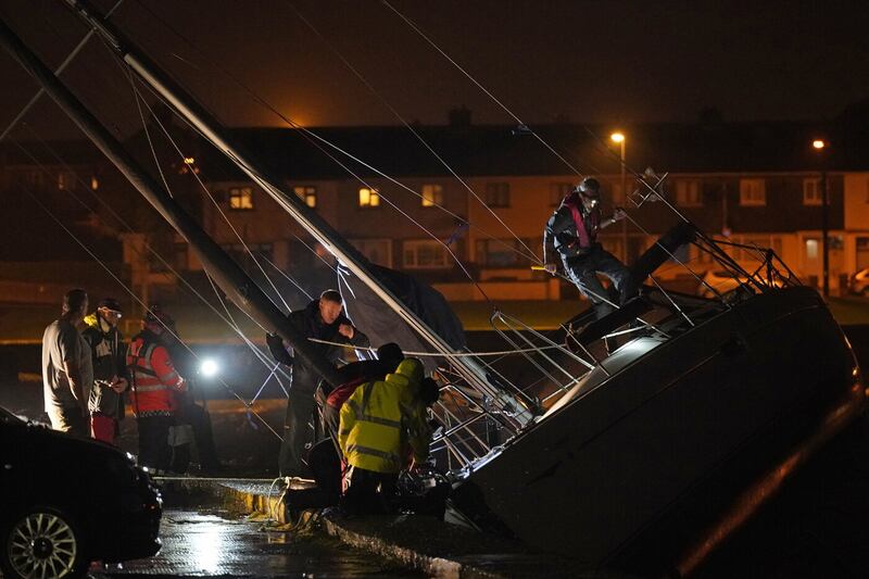 Members of the coast guard inspect the damage to a boat after it broke free from its berth and crashed into the harbour during Storm Betty in Dungarvan, County Waterford. Picture by Niall Carson/PA Wire.