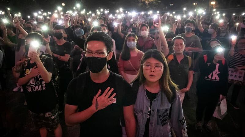 Demonstrators hold their phones aloft as they sing Glory To Hong Kong during a rally in 2019 (Mark Schiefelbein/AP)