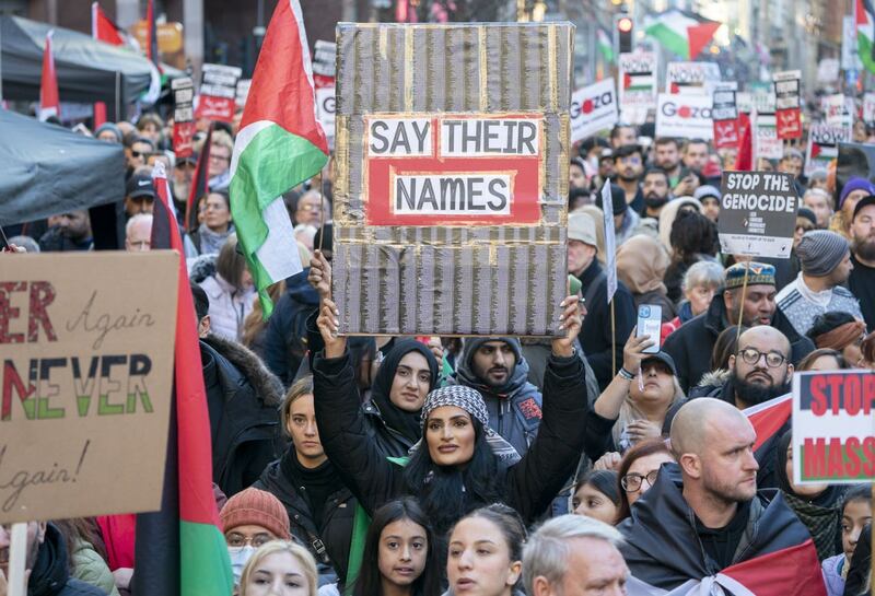Woman holding a sign saying 'say their names' at a pro-Palestinian rally