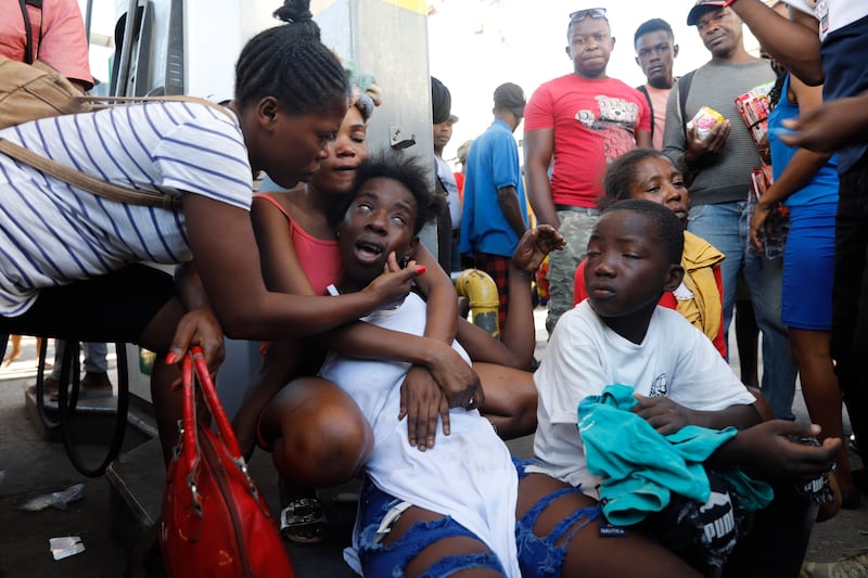 The relative of a person found dead in the street reacts after an overnight shooting in the Petion Ville neighbourhood of Port-au-Prince (Odelyn Joseph/AP)