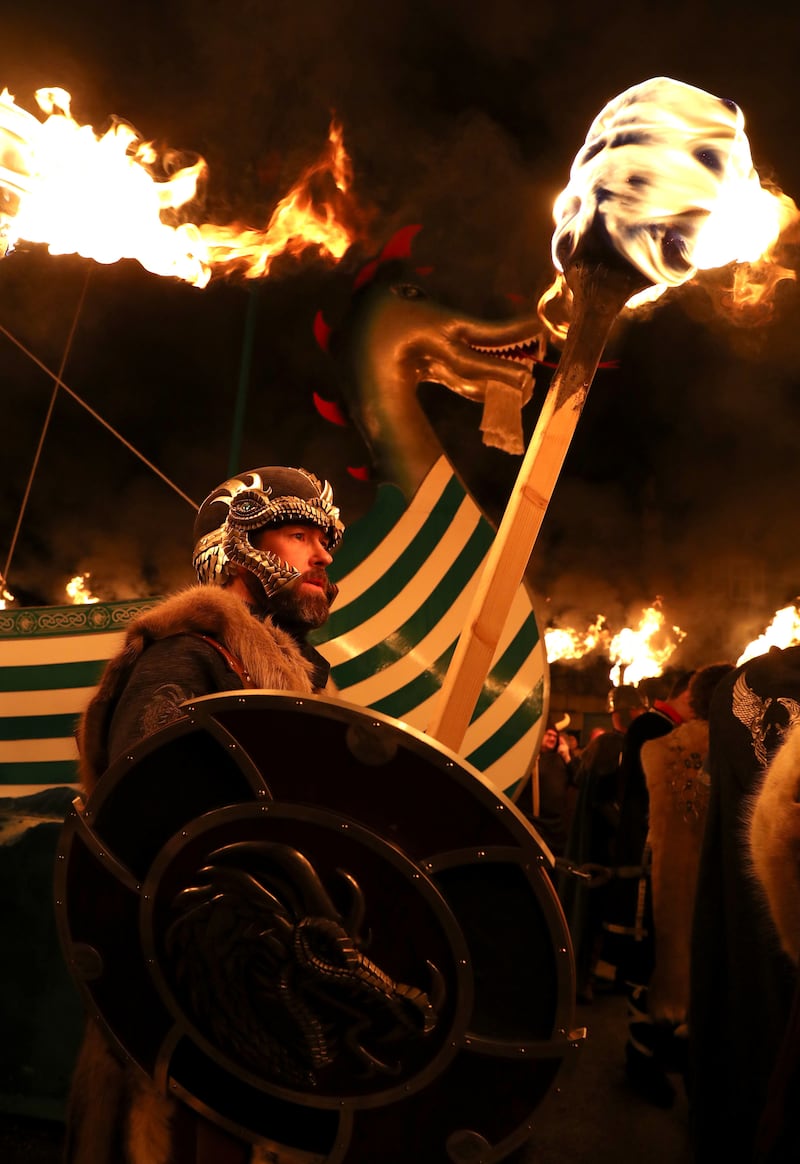 Members of the Jarl Squad march beside the Galley as they head through Lerwick ahead of the Galley being set on fire on Shetland Isles during the Up Helly Aa Viking festival 