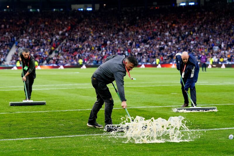 Ground staff clear water from the pitch