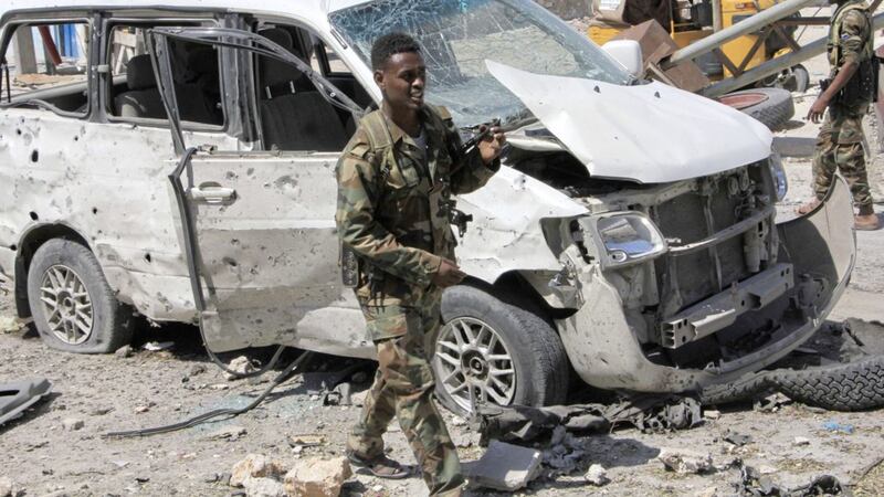 Somali soldiers walk near a vehicle, at the scene of a suicide car bomb attack in Mogadishu, Somalia. Picture by Farah Abdi Warsameh, Associated Press