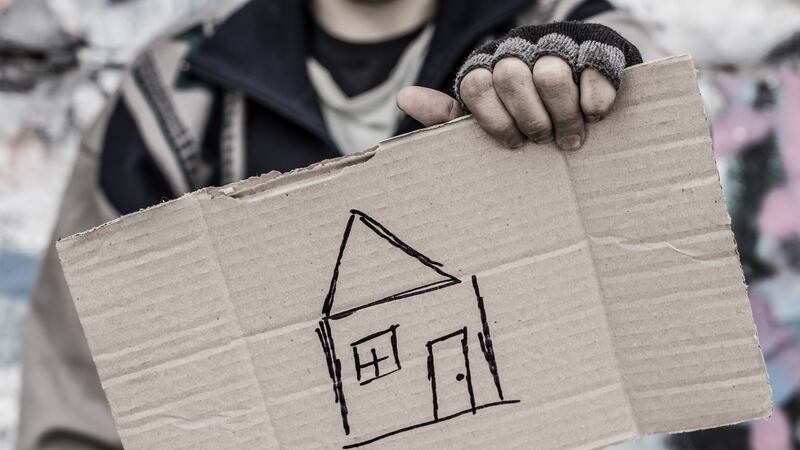 Young homeless man holding sign with painted house