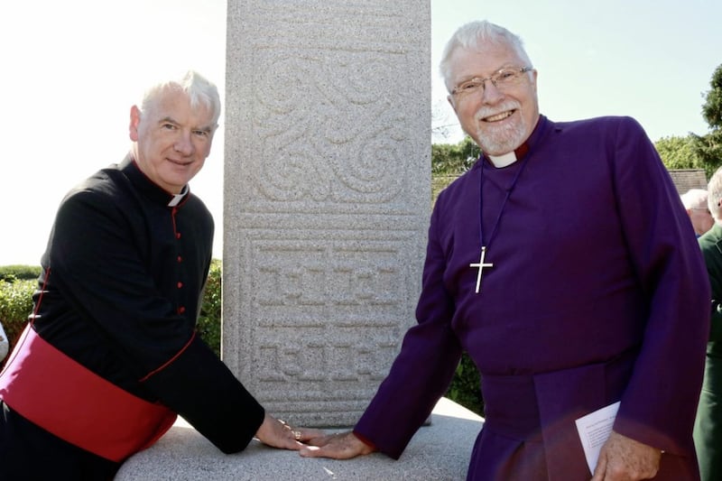 Church of Ireland Bishop of Down and Dromore Harold Miller and Catholic Bishop of Down and Connor Noel Treanor place their palms in a hand-shaped depression on the base of St Patrick&#39;s Cross as a symbol of the centrality of the cross to Christianity 