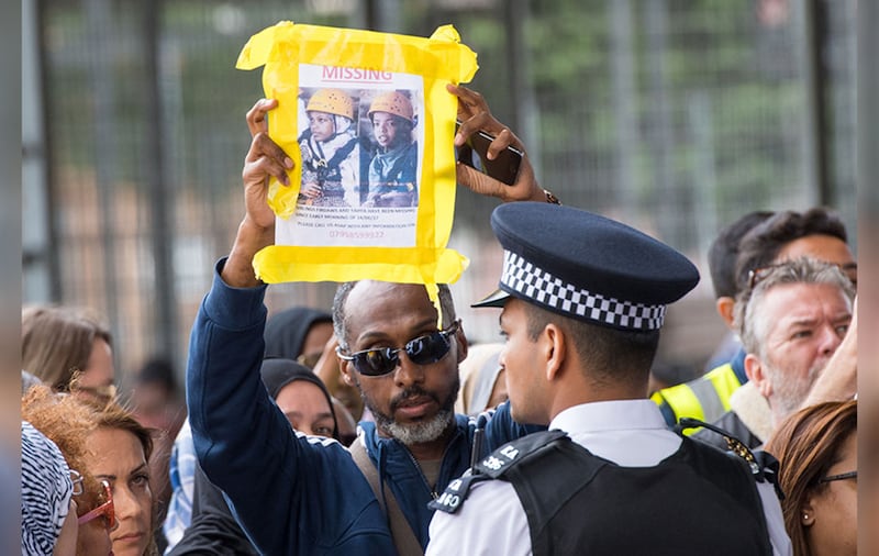 A man hold up a missing persons poster during a visit by Queen Elizabeth II and the Duke of Cambridge to the Westway Sports Centre, London, which is providing temporary shelter for those who have been made homeless in the Grenfell Tower fire.&nbsp;Picture by Dominic Lipinski, PA Wire