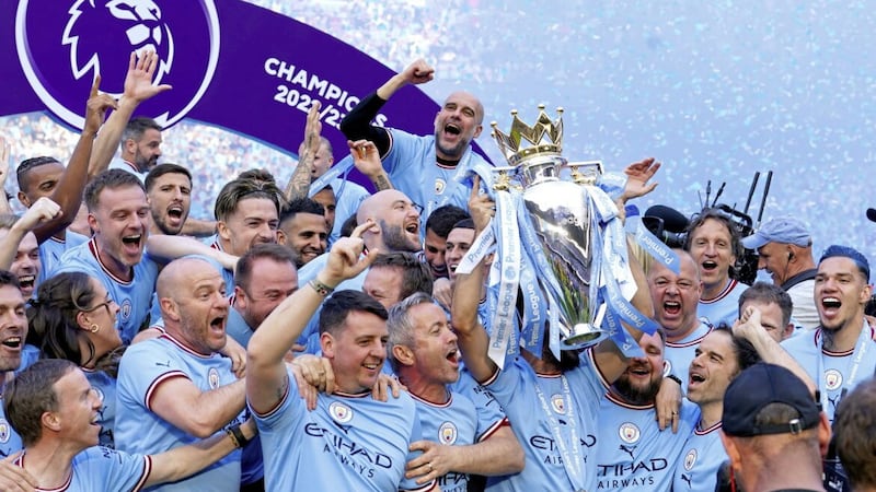 Manchester City players and staff celebrate with the Premier League trophy. 
