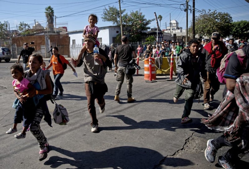 Migrants run toward the US after breaking past a line of Mexican police at the Chaparral border crossing in Tijuana, Mexico, on November 25 2018, near the San Ysidro, California entry point. Picture by Ramon Espinosa, Associated Press 