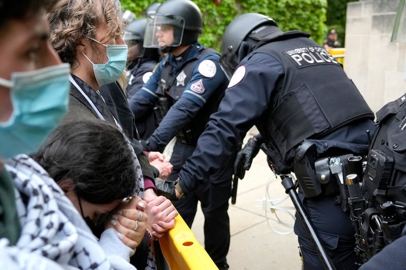 A pro-Palestinian protester rests her head on her clasped hands while she stands before police officers at the University of Chicago (Charles Rex Arbogast/AP)