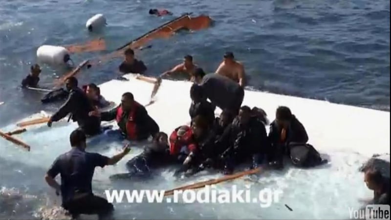 A rescuer helps migrants from a capsized vessel in the eastern Aegean island of Rhodes, Greece in May 2015 