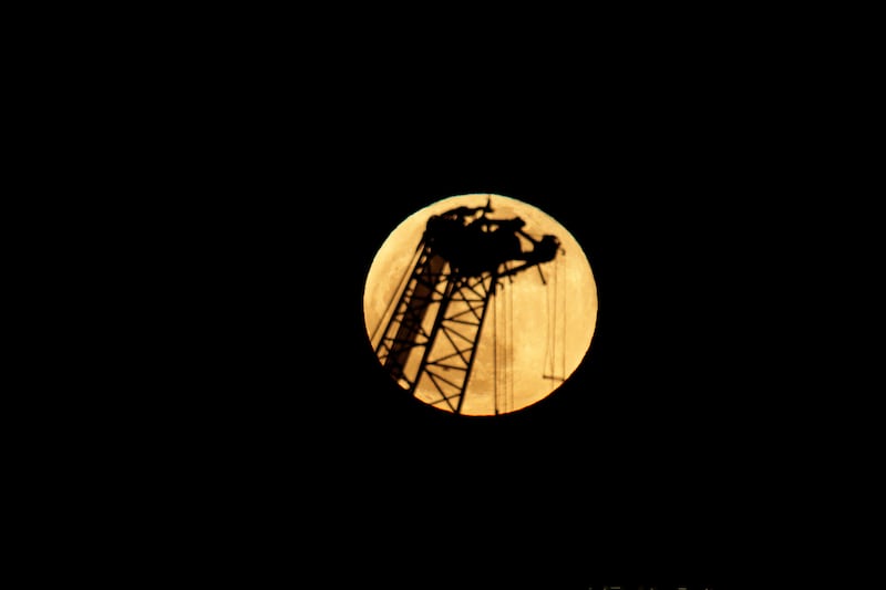 Orange moon behind a crane