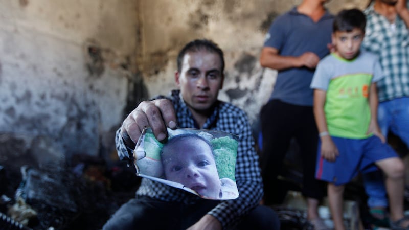 A relative holds up a photo of 18-month-old Ali Dawabsheh who was killed in an arson attack on his home in the West Bank. Picture by Majidi Mohammed, AP Photo