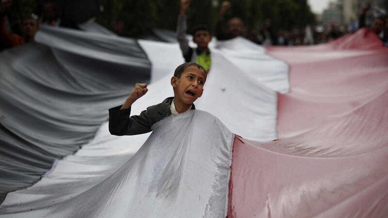 A boy chants slogans through a gap in a national flag raised by Shiite rebels, known as Houthis, during a protest against Saudi-led airstrikes in Sanaa, Yemen, last month. Picture by Hani Mohammed, Associated Press