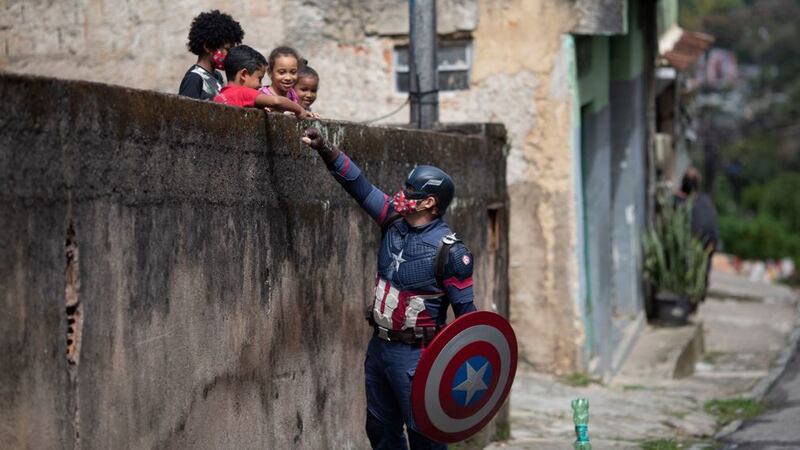 &nbsp;Military police officer Everaldo Pinto, dressed as superhero Captain America, greets children in Petropolis, Rio de Janeiro state, in Brazil. The officer&nbsp;&nbsp;advises children on the need to protect themselves against Covid-19, distributing kits equipped with cleaning products and protective face masks. Picture by Silvia Izquierdo, AP