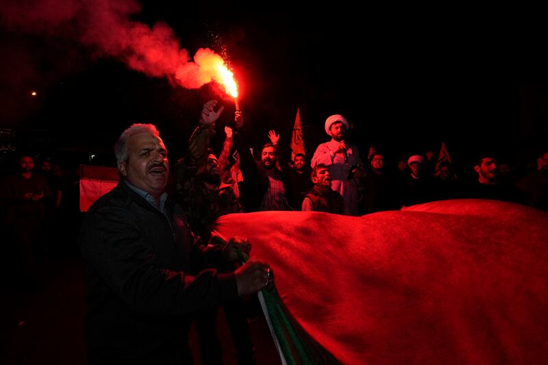 An Iranian demonstrator ignites a flare as others carry a Palestinian flag during an anti-Israeli gathering at the Felestin (Palestine) Square in Tehran, Iran (Vahid Salemi/AP)