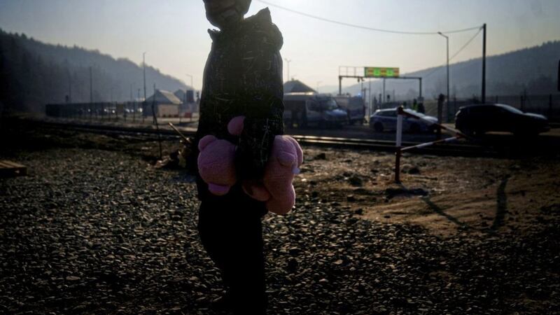 A young boy from Ukraine holds a pink teddy bear after crossing over a border point with his family in Kroscienko, in south east Poland. Picture by Victoria Jones/PA Wire. 