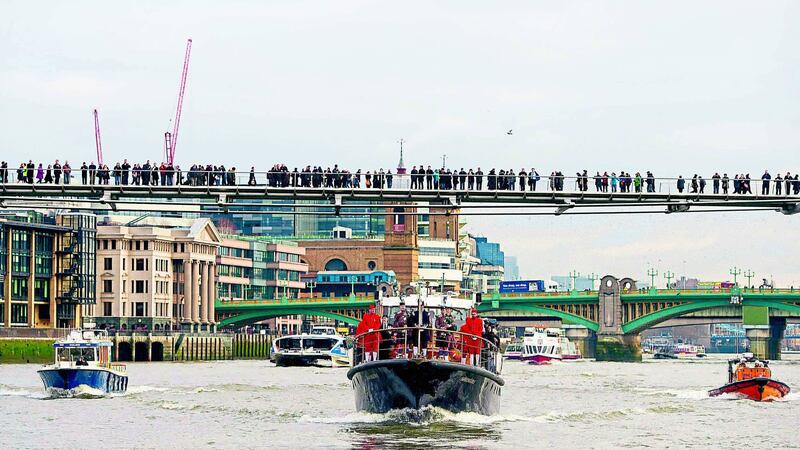 Crowds watch from the Millennium Bridge as the Havengore barge passes along the River Thames, in central London, at the head of a procession recreating the journey it made 50 years ago carrying the coffin of former British prime minister Sir Winston Churchill. Picture by Press Association &nbsp;