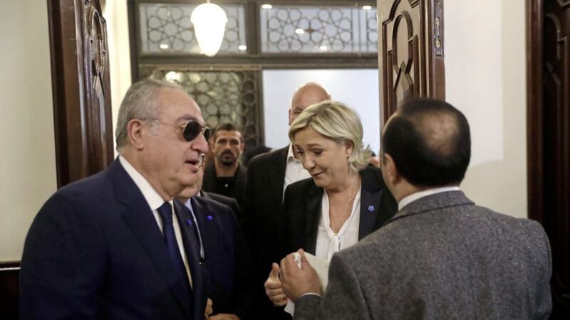 An aide of Lebanon&#39;s Grand Mufti Sheikh Abdel-Latif Derian, right, holds a head scarf as he tries to convince French far-right presidential candidate Marine Le Pen, centre, to wear it. Picture by Hussein Malla, Associated Press 