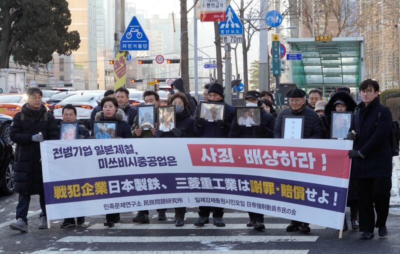 Victims relatives’ outside the Supreme Court in Seoul, South Korea, with a sign reading ‘Mitsubishi Heavy Industries should compensate and apologise’ (Ahn Young-joon/AP)