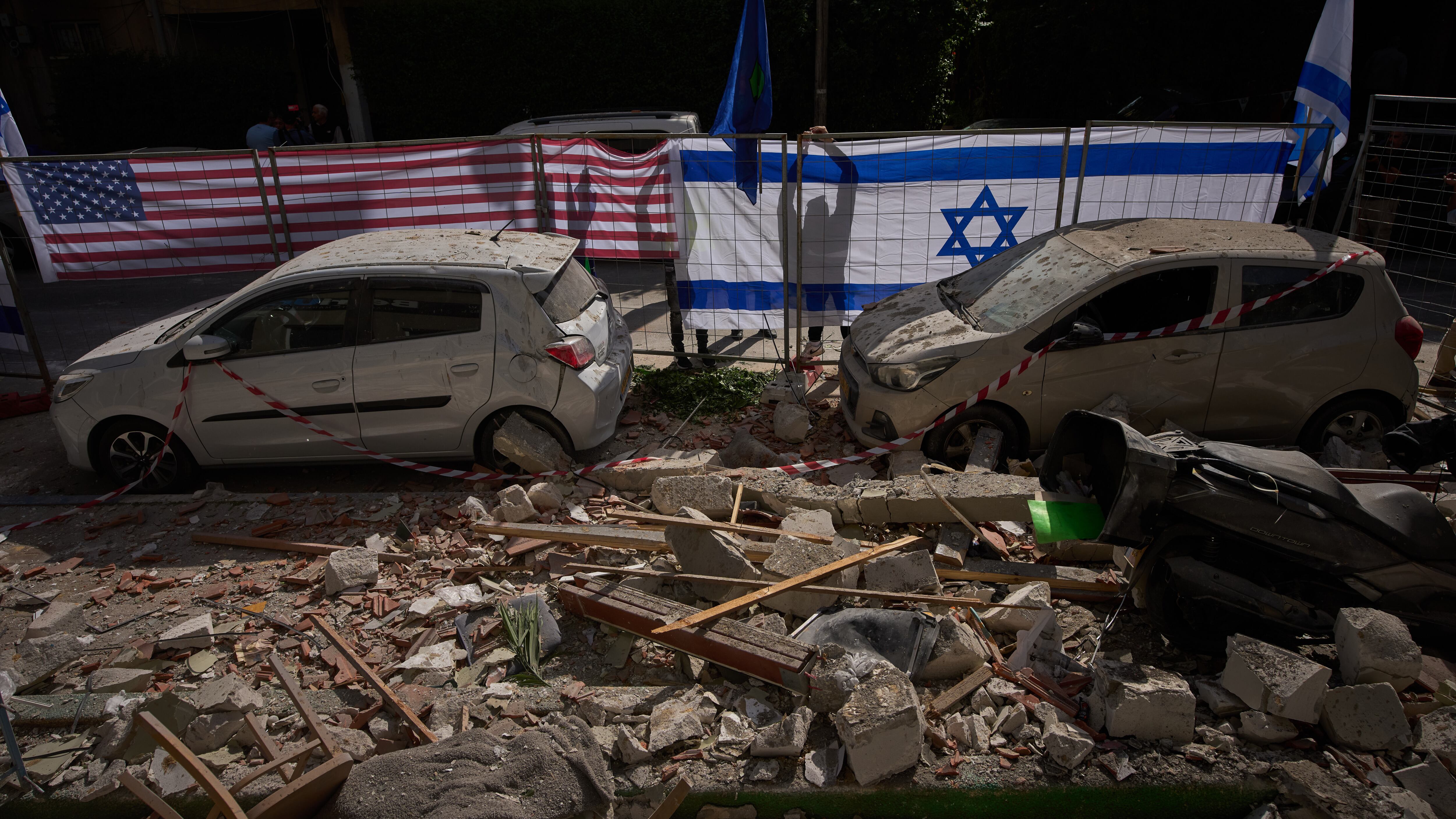 Israeli authorities hang Israeli and US flags at a site struck by an Iranian missile that killed two people in Ramat Gan, Israel (Oded Balilty/AP)