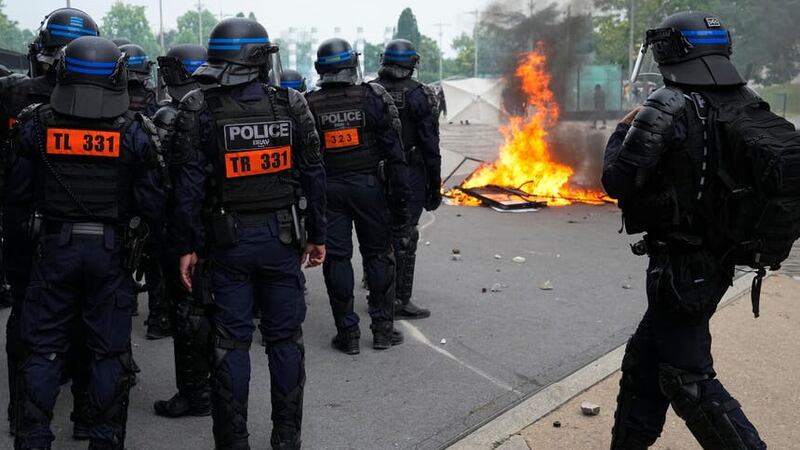 Riot police officers stand by a fire after a march for Nahel in Nanterre (Michel Euler/AP)