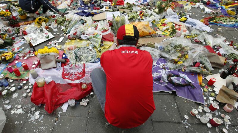 Two men help re-adjust the tributes left for the victims of the recent bomb attacks in Brussels, following heavy rain in the Place de la Bourse in Brussels. Picture by&nbsp;Alastair Grant, Associated Press&nbsp;