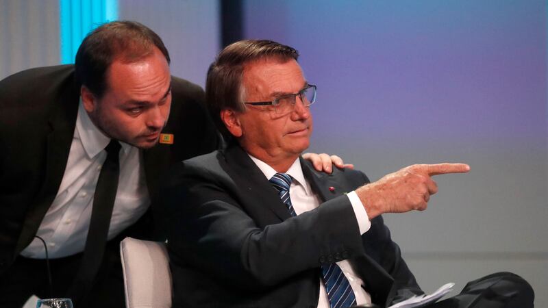 Carlos Bolsonaro, son of Brazil’s ex-president Jair Bolsonaro, whispers in his father’s ear during a presidential debate in Rio de Janeiro, Brazil, in 2022 (Bruna Prado/AP)