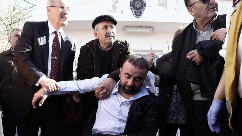 Medics and bystanders help a collapsed relative of a victim outside the medical forensics site in Ankara yesterday Picture by: Burhan Ozbilici/AP 
