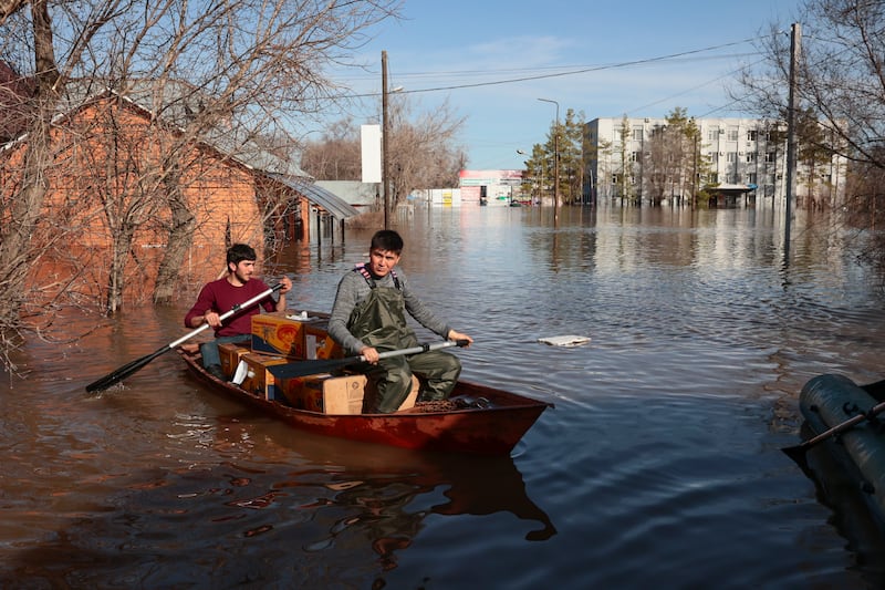 Two men ride a boat delivering food in a flooded area in Orenburg, Russia (AP)