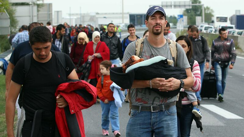 A man holds a baby as refugees walk towards Vienna after crossing the Hungarian-Austrian border &nbsp;