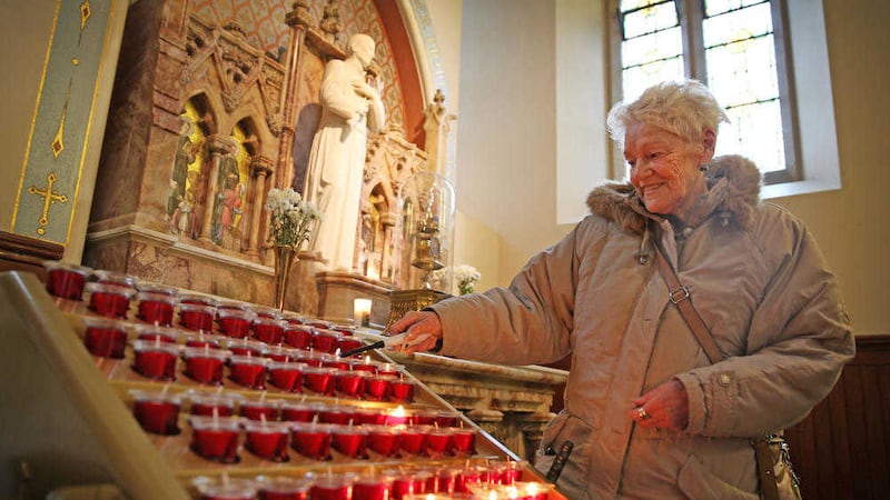 Isabel McCartney lights a candle at Clonard in remembrance of Fr Gerry Reynolds who passed away on Monday. Picture by Mal McCann.