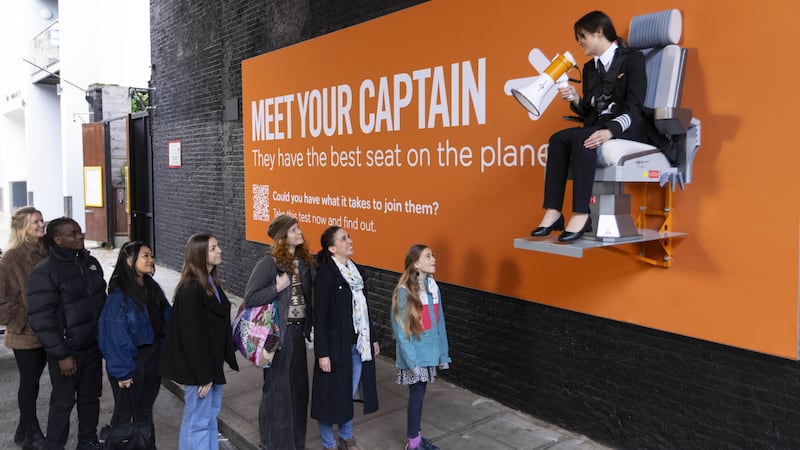 Pilot Sarah Ackerley sits on an interactive billboard in London at the launch of an easyJet campaign