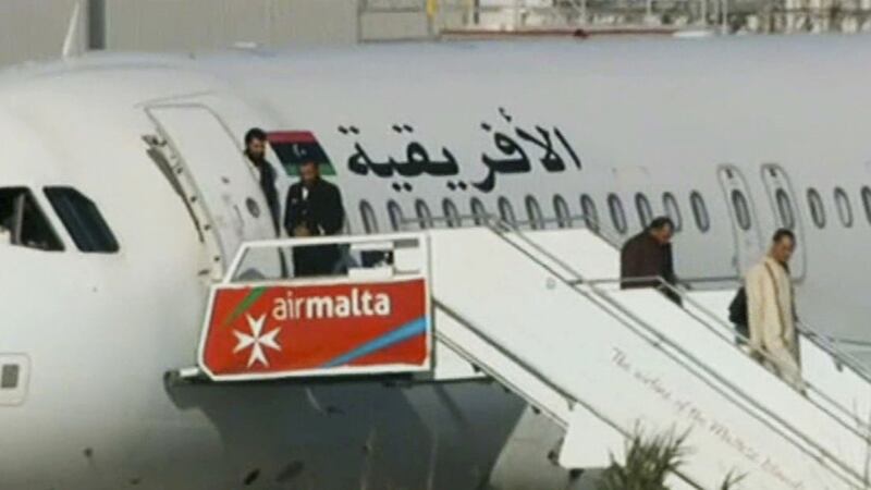 An Afriqiyah Airways plane stands on the tarmac at Malta's Luqa International airport as passengers depart, Friday, December 23, 2016. Hijackers diverted the Libyan commercial plane to Malta on Friday and threatened to blow it up with hand grenades, Maltese authorities and state media said