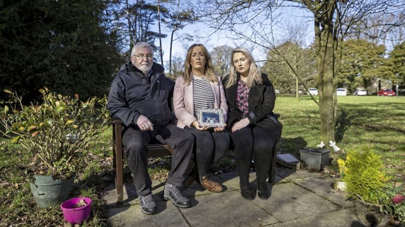Lisa Dorrian&#39;s father John and her sisters Michelle (centre) and Joanne (right) sitting at a memorial bench to Lisa at Castle Park in Bangor beside a cherry blossom tree planted by her friends.   
