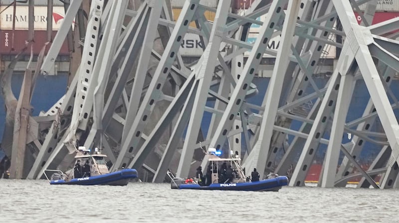 Police boats work around a cargo ship that is stuck under part of the structure of the Francis Scott Key Bridge (Steve Helber/AP)